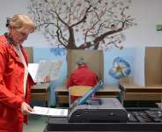 A woman places her ballot into an electronic ballot box during the general election in Sarajevo on October 4, 2026. - Armin Durgut, AP
