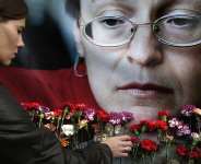 A file image taken on October 7, 2009 of a woman placing flowers before a portrait of slain Russian journalist Anna Politkovskaya in Moscow. - Pavel Golovkin, AP
