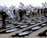 People carrying Israeli flags walk through a commemorative installation set up on the beach in Tel Aviv to mark the third anniversary of Hamass October 7 attack on Israel. - AFP