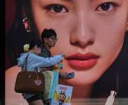 Shoppers with their purchased goods walk by a luxury cosmetic store at an outdoor shopping mall, in Beijing, Monday, April 14, 2025 -  Andy Wong, AP