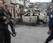 Police walk past a burned car used as a roadblock during a police operation against alleged drug traffickers in the Complexo do Alemao favela in Rio de Janeiro on Oct. 28, 2025. -  Silvia Izquierdo, AP