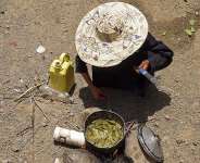 A displaced Yemeni woman boils leaves to feed her grandchildren at the Al-Manij displacement camp near Taez, south-west Yemen, 21 May. - AFP - AHMED AL-BASHA