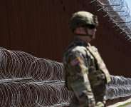 A member of the US military looks on in front of newly-installed concertina wire lining one of two border walls separating Mexico from the United States, March 21, 2025 -  Gregory Bull, AP
