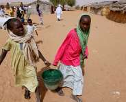 Sudanese refugees carry water supplies near a polling station in the refugee camp of Zamzam, on the outskirts of El Fasher, Darfur, in April 2010. -  AP - Nasser Nasser
