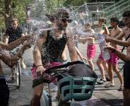 A group of teenagers throw water over a cyclist at the Canal Saint-Martin in Paris, 24 June. - AFP - SIMON WOHLFAHRT