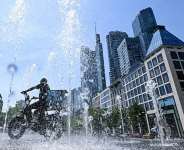 A man rides his bicycle through a fountain outside the banking district in central Frankfurt am Main, western Germany, on June 26, 2026. -  Kirill Kudryavtsev, AFP