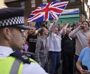 Anti-migration protesters wave a Union Flag during a demonstration over housing for asylum seekers in Orpington near London, 22 August 2025. -  Alberto Pezzali / AP