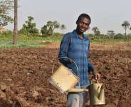 Aboubakar, 18, waters crops alongside his father on the family farm in Djougou as he rebuilds his life through agriculture after returning home. Photo: IOM/Rodrigue Combey Komla Fumey
