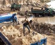 Miners shovel sand into trucks in an area destroyed by sand mining on the outskirts of Gunjur in the Gambia. - AFP - JOHN WESSELS