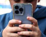 A boy looks at social media on his smartphone. The European Union is weighing how to regulate childrens access to online networks. -  AFP - DAVID GRAY