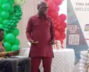STU Lecturer outdoors book on Ghana’s land tenure systems