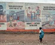A child returning from school stops to look at Ebola awareness illustrations displayed on the signboards of the Ebola Treatment Center in Munigi on June 2, 2026. -  Jospin Mwisha, AFP