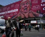 Pedestrians walk past a billboard depicting US President Donald Trump being grabbed by the neck alongside the message Revenge is inevitable in English and Farsi, in Tehran on July 27, 2026. -  Vahid Salemi, AP
