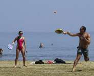A man and woman play on the beach as other people enjoy the sea during a hot day in southern coastal city of Larnaca on the Mediterranean island of Cyprus, March 31, 2024 -  Petros Karadjias, AP