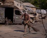 A local resident removes scattered debris next to destroyed vehicles the day after a Russian missile and drone attack in Kyiv, Friday, Aug. 21, 2026. -  Francisco Seco, AP