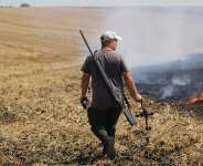 A farmer carries a part of a Russian FPV drone that he shot down with a rifle as he watches a field burn following an air attack in the Kharkiv region, Ukraine, Wednesday, August 5, 2026. -  Andrii Marienko, AP