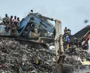 Residents and rescue workers use an excavator to search for bodies following a landslide that occurred overnight at the Dar-es-Salam landfill in Conakry, Guinea, on 23 August 2026. - AFP - -