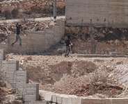 Israeli settlers jump over the garden wall as they make their way towards a Palestinian home under construction in the village of Qusra, which has faced escalating settler violence over the past month. -  Jaafar Ashtiyeh, AFP