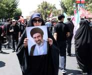 An Iranian woman holds a portrait of Iranian supreme leader Ayatollah Mojtaba Khamenei as Shia Muslim devotees take part in a mourning procession marking Arbaeen in Tehran on August 4, 2026. -  AFP