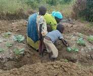 A mother cultivates a permagarden with her children Photo Credit The Permagardens Foundation