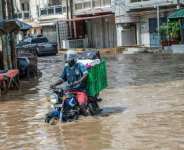 A man steers his motorcycle through Dakars flooded streets on October 5, 2026.  By SEYLLOU (AFP)
