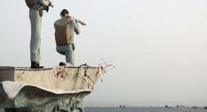 A statue of Iranian military members stands as vessels in the Strait of Hormuz are visible near the beach of Bandar Abbas, Iran, 22 May, 2026. - via REUTERS - Majid-Asgaripour