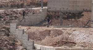 Israeli settlers jump over the garden wall as they make their way towards a Palestinian home under construction in the village of Qusra, which has faced escalating settler violence over the past month. -  Jaafar Ashtiyeh, AFP