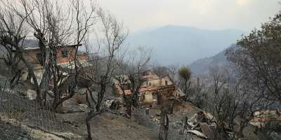 Damaged buildings are seen on a scorched hill after a forest fire swept through the area in Bordj Thar, a town and commune in Algerias northeastern Jijel Province, on August 27, 2026. Algerian President Abdelmadjid Tebboune on August 27 declared a three