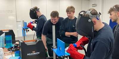 A group of students learning how to weld with welding simulators