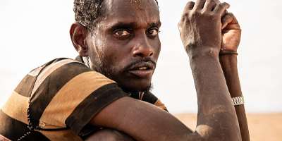 Omar, an Ethiopian migrant, is treated for dehydration and exhaustion by IOM’s Mobile Unit in the Djiboutian desert. Chances of survival are low for migrants crossing the desert in extreme temperatures and the weakest are often left behind. Photo: IOM 2020/Alexander Bee