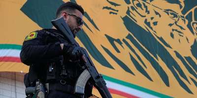 A police officer stands guard near a banner with portraits of former Iranian leaders Ayatollah Khomeini and Ayatollah Ali Khamenei in Tehran, Iran on April 29, 2026. - Vahid Salemi, AP