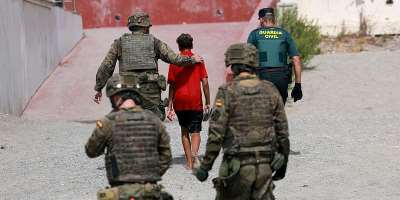 A minor from Morocco is escorted by Spanish security forces after attempting to cross into Ceuta by sea, 1 August. - REUTERS - Violeta Santos Moura