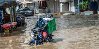 A man steers his motorcycle through Dakars flooded streets on October 5, 2026.  By SEYLLOU (AFP)