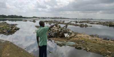 A resident points to plastic and other waste at a lagoon in Abidjan.  By Sia KAMBOU AFPFile