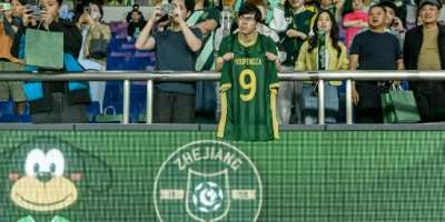 A Zhejiang FC fan holds up a shirt of Aaron Boupendza, the Gabon international footballer who was found dead earlier on Wednesday after an apparent fall from the 11th floor of a building.  By - (AFP)