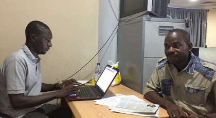 Hamza Idris (left), an editor with the Daily Trust newspaper, sits with colleague Hussaini Garba Mohammed in their office in the Nigerian capital, Abuja, in February 2019. The office was raided in January by the military, who seized 24 computers. (CPJ/Jonathan Rozen)