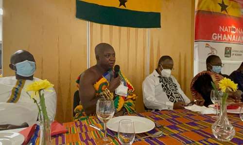 Nana Kota Ntiamoah with microphone dressed in cloth speaking during the inauguration of the NUGN in Bergen. Seated with him are the Ghana's Ambassador to Norway, Jennifer Lartey and her team from the Ghana Embassy, Oslo