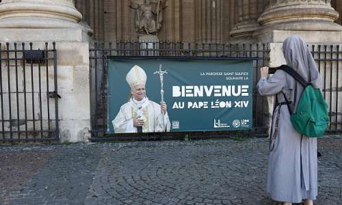 A nun takes a picture of a banner welcoming Pope Leo to France, outside Saint Sulpice church in Paris on 23 September 2026. -  REUTERS - Abdul Saboor