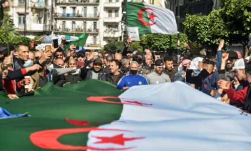 Algerians wave national flags during an anti-government protest in the capital Algiers on Friday. By RYAD KRAMDI (AFP)