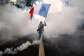A protestor waves a French flag among tear gas smokes while taking part in a nationwide demonstration in Lyon, France, on October 31, 2026. -  Jeff Pachoud, AFP