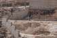 Israeli settlers jump over the garden wall as they make their way towards a Palestinian home under construction in the village of Qusra, which has faced escalating settler violence over the past month. -  Jaafar Ashtiyeh, AFP