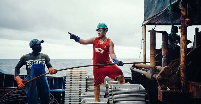 Chinese and local staff operate machinery on a fishing-boat