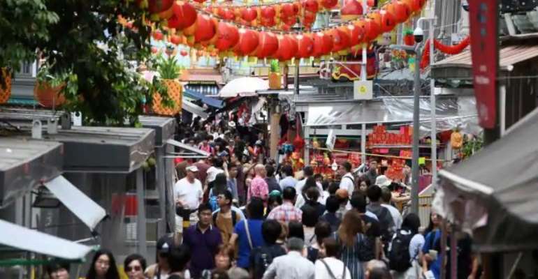 People walk along a crowded alleyway past stalls selling gifts and decorative items in the Chinatown district of Singapore on February 19, 2018. Singapore unveiled its 2018 budget on February 19, with economists predicting the city-state raising its goods