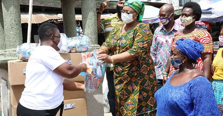 Mrs Amoah presenting the facemask and sanitizers to the market women.