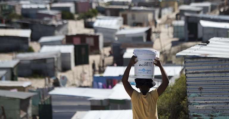 A woman carries a bucket of fresh water to an informal settlement in Khayelitsha,Cape Town. - Source: