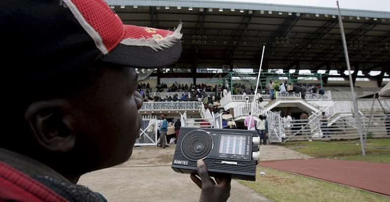 A party agent listens to the radio as electoral officials confirm and tally votes from polling stations in Nairobi, Kenya in 2007. - Source: Stephen Morrison/EPA