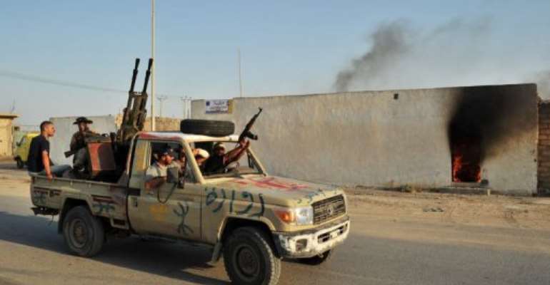 Libyan rebels drive through a street after defeating loyalist troops in Al-Jamil in 2011. By Carl de Souza (AFP/File)