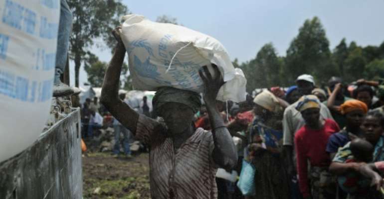 A displaced Congolese woman volunteers to offload sacks of maize-flour during a food aid distribution at a camp for the internally displaced in Mugunga, on November 24, 2012. By Tony Karumba (AFP/File)