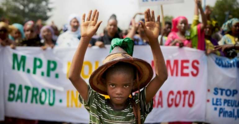 A Fulani boy protests in front of a sign saying 'Stop the Genocide' during a silent march in Bamako on June 30. By MICHELE CATTANI (AFP)