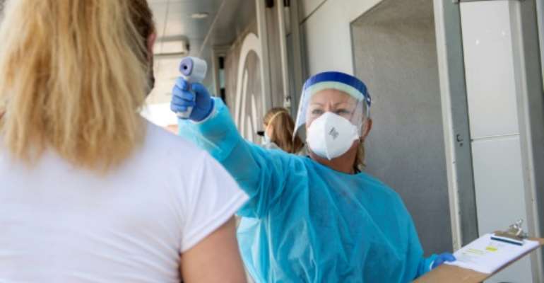 A health worker takes a patient's temperature before their test in Los Angeles, California. By VALERIE MACON (AFP/File)